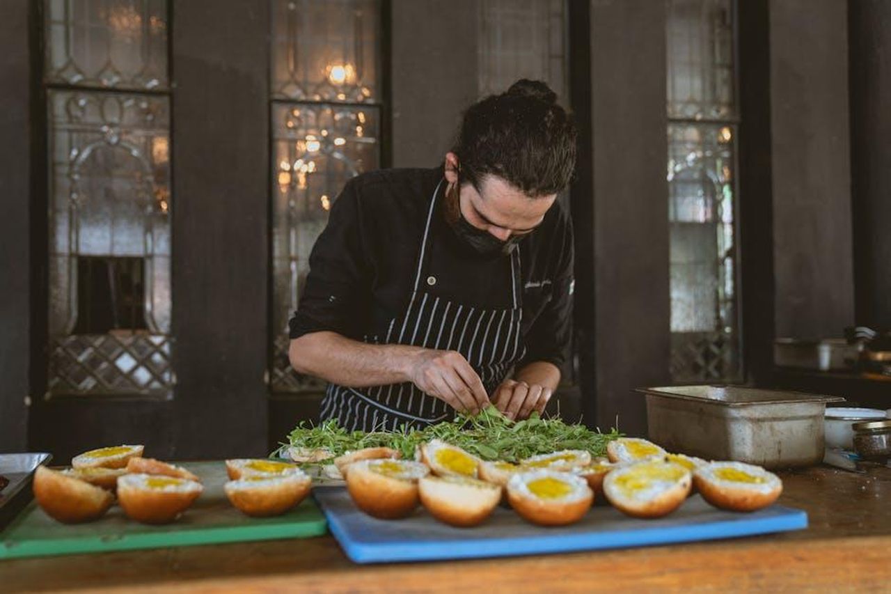 Assemblaggio_del_sandwich_di_salumi_Y3KJNlqJnB - Confidenze24 Source: Los Muertos Crew - pexels - Chef focuses on preparing gourmet sandwiches with fresh ingredients in a stylish restaurant setting.