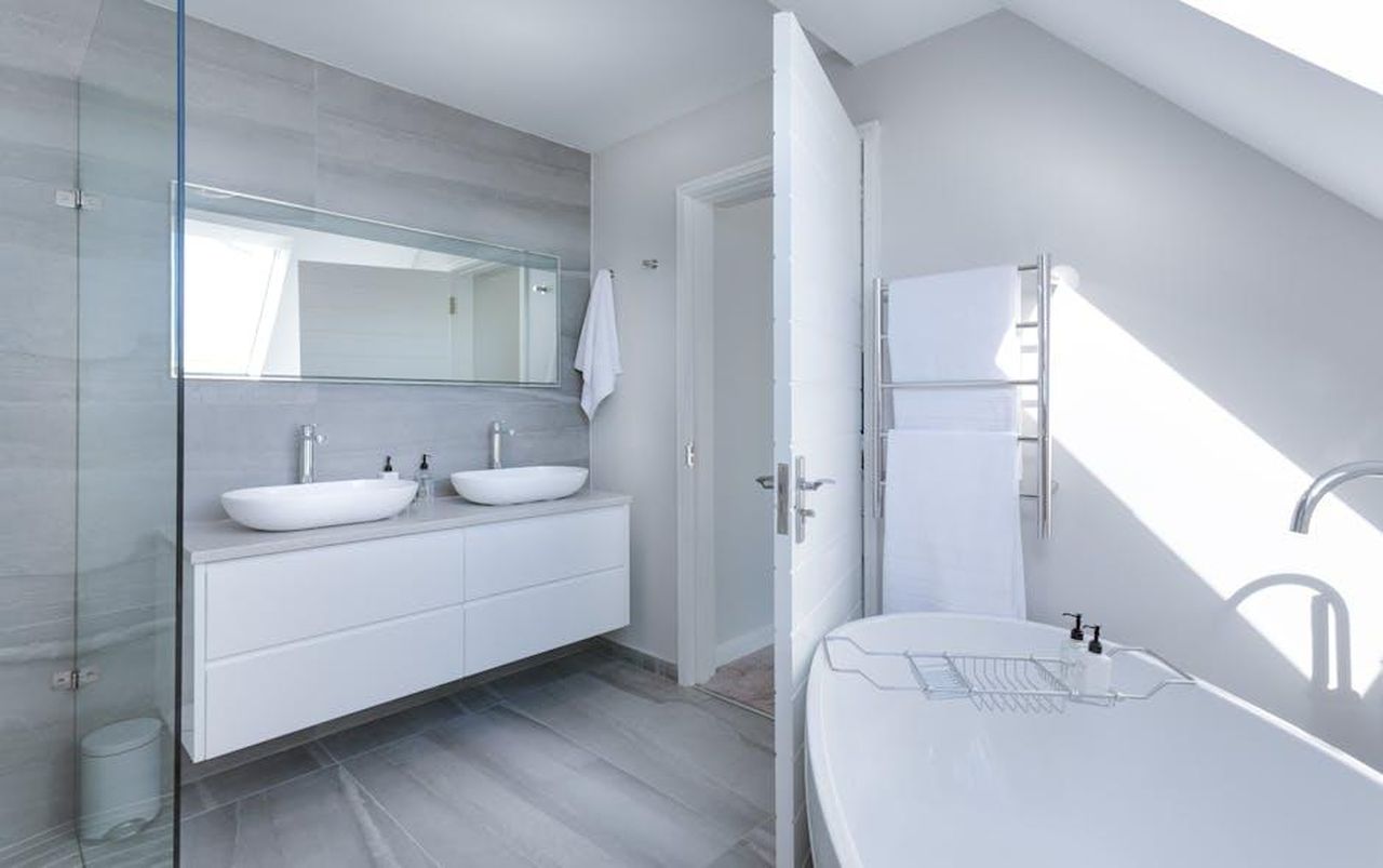 Bagni_separati_per_lui_e_per_lei_XbvT5YOkg6 - Confidenze24 Source: Jean van der Meulen - pexels - Sleek contemporary bathroom with bathtub and twin sinks, showcasing minimalist design and luxury.