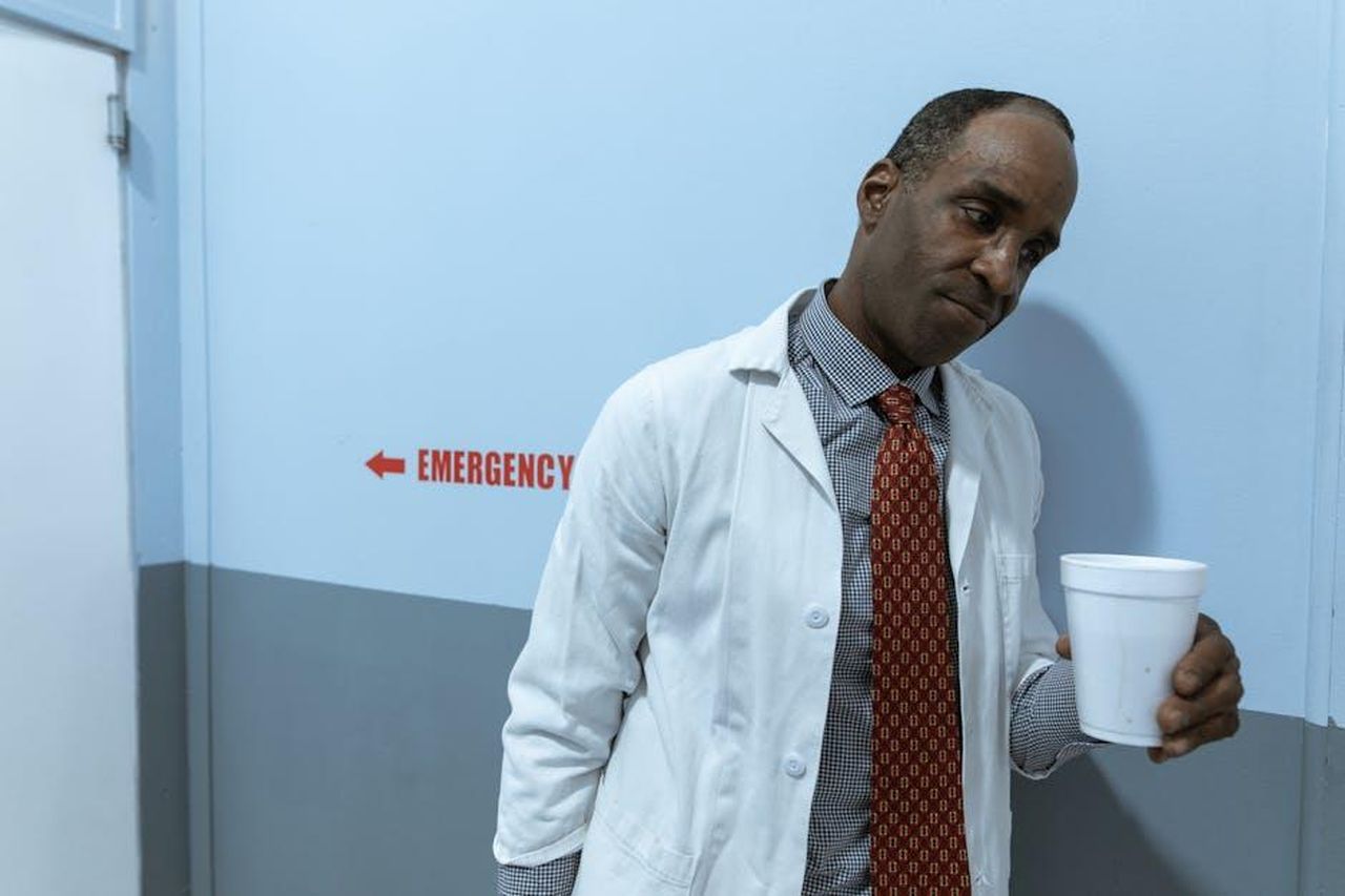 Betsy_morir_in_Coronation_Street_oSHbeZweuc - Confidenze24 Source: RDNE Stock project - pexels - A healthcare worker in a lab coat holding a cup in a hospital corridor by the emergency section.