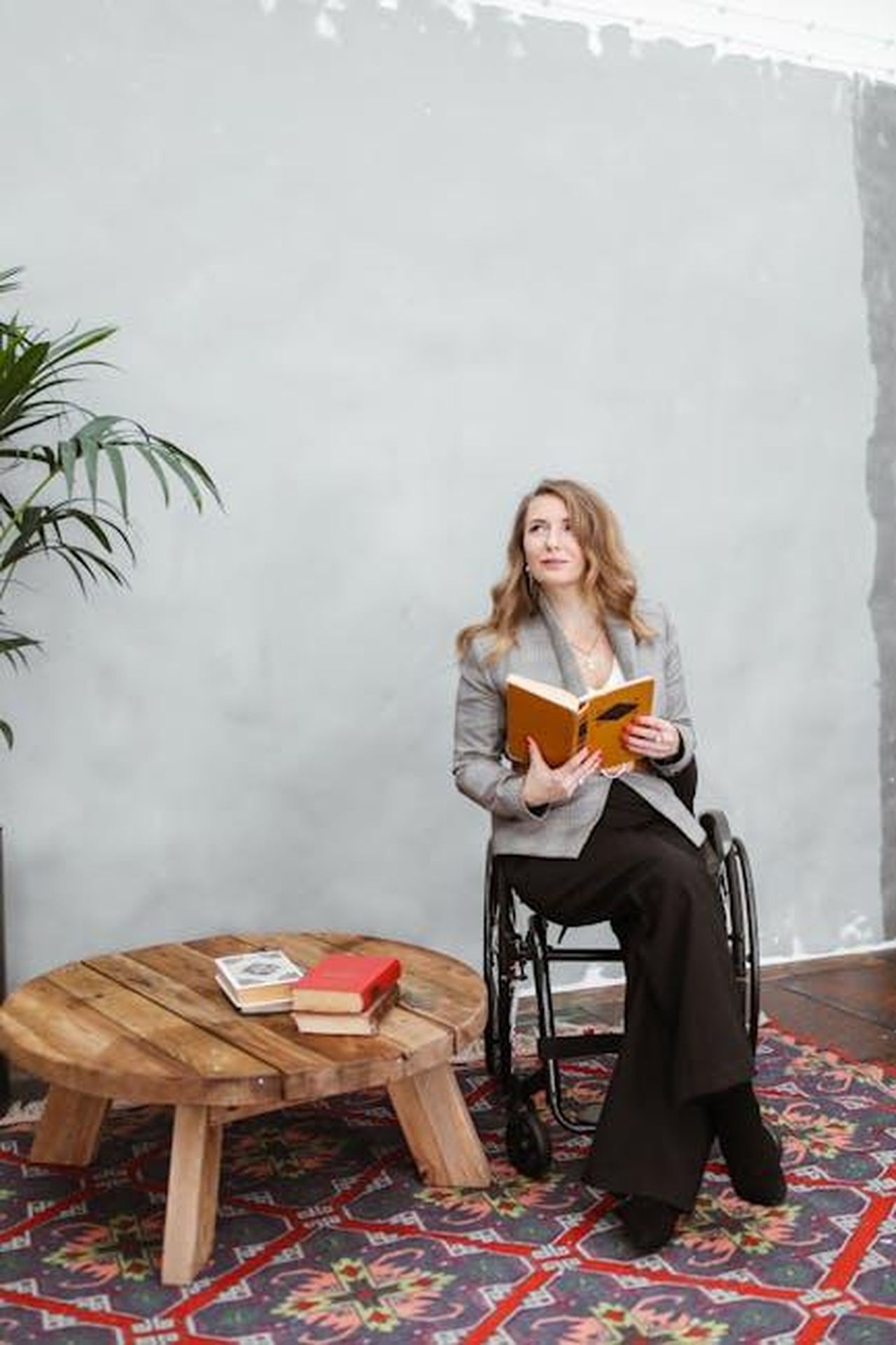 Big_Sean_Promuove_il_Suo_Libro_Go_Higher_Kt80t3nPDh - Confidenze24 Source: Polina Tankilevitch - pexels - A woman in a wheelchair reads a book in a cozy indoor setting.