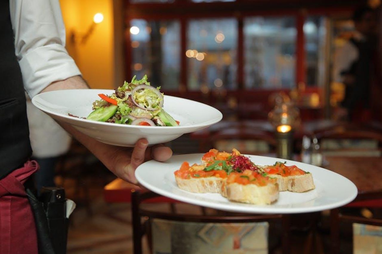 Bill_Rancic_Un_imprenditore_di_successo_nPrPNpNYJr - Confidenze24 Source: Pixabay - pexels - A waiter serves a fresh salad and hors d'oeuvres in a cozy restaurant setting.