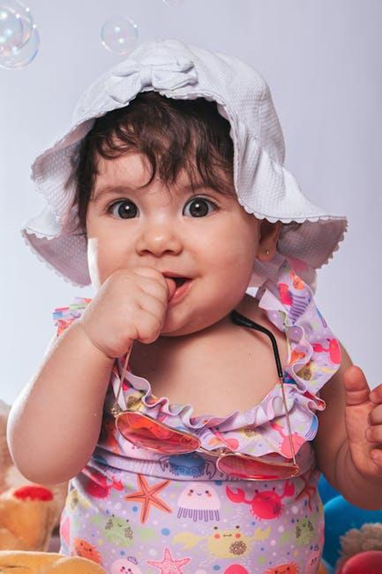Boris__il_backmarker_YMvJ0dBsiW - Confidenze24 Source: Eric Moura - pexels - Cute baby in a hat, colorful outfit, surrounded by bubbles, capturing playful innocence.