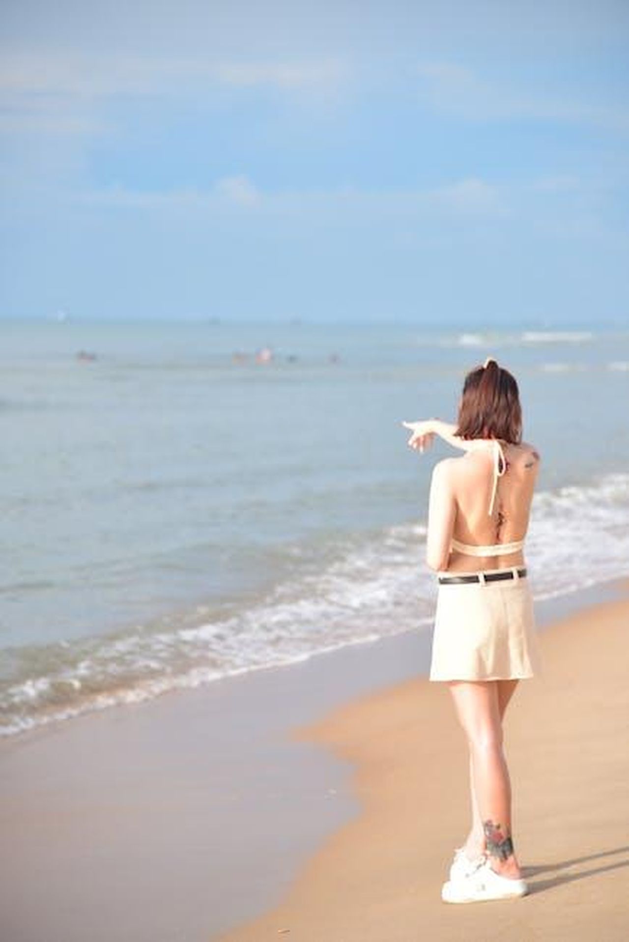 C_spazio_per_tutti_nel_mondo_del_lifestyle_z22sxCKUUP - Confidenze24 Source: Sóc Năng Động - pexels - Back view of a woman on a beach pointing towards the horizon under a clear blue sky.