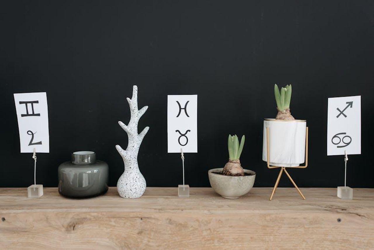 Cancro_22_giugno__22_luglio_XdR47D53oq - Confidenze24 Source: Pavel Danilyuk - pexels - Modern decor featuring potted plants and zodiac symbols on a wooden table with a stylish touch.