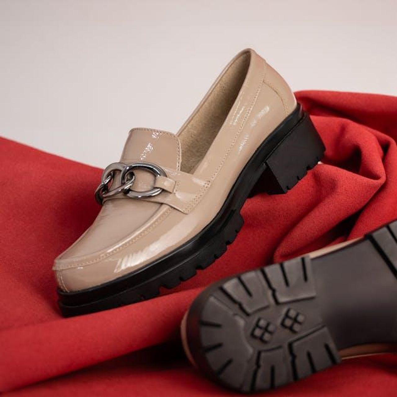 Caratteristiche_delle_On_Cloudsurfer_2_JWaqb8In7X - Confidenze24 Source: José Martin Segura Benites - pexels - Classy beige loafers with chunky soles and silver chain design on a vibrant red fabric backdrop.