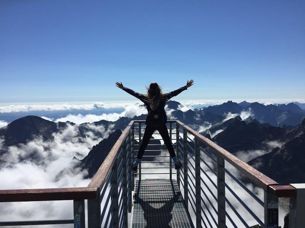 Carl_era_un_uomo_di_successo_eC5CvGoykR - Confidenze24 Source: Nina Uhlikova - pexels - A woman stands on a viewing platform in Vysoké Tatry, Slovakia, surrounded by clouds and mountains, embracing freedom.