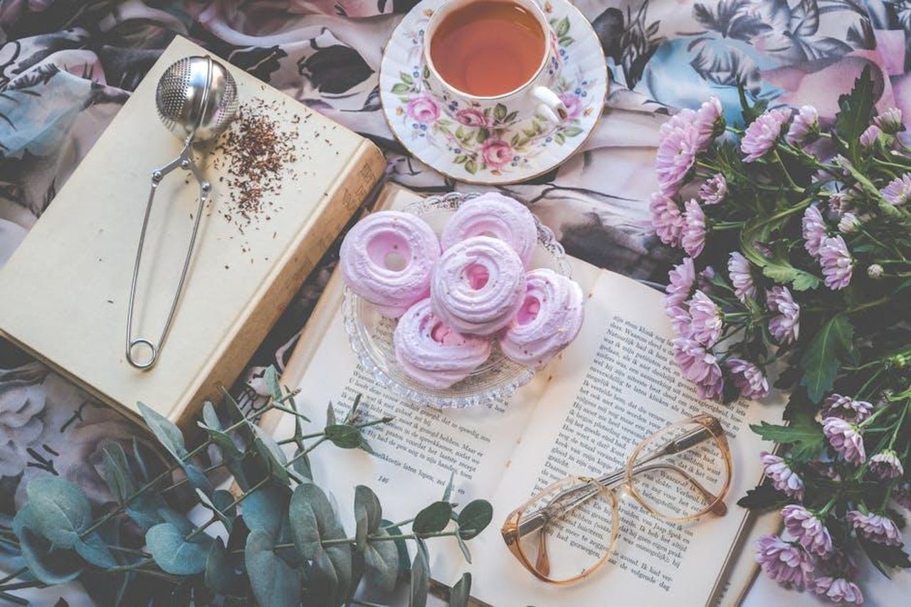 Celebrit_e_le_loro_raccomandazioni_di_libri_vfmlLHahzL - Confidenze24 Source: Ylanite Koppens - pexels - Delicate flatlay with pink pastries, tea, flowers, book, and glasses for a romantic setting.