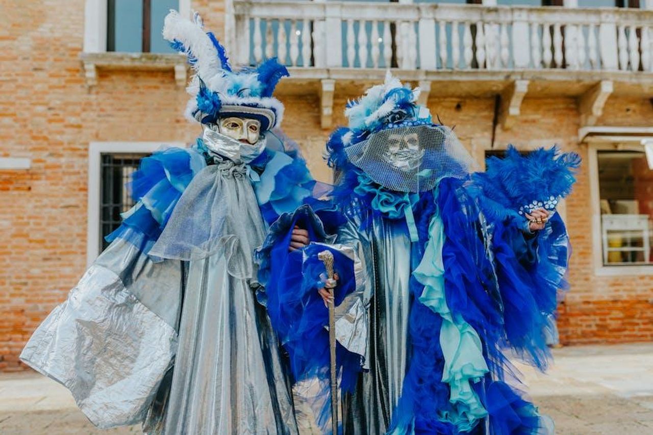 Celebrit_presenti_alla_sfilata_di_Chanel_wYZngVe1TT - Confidenze24 Source: Helena Jankovičová Kováčová - pexels - Elegant Venetian carnival costumes with decorative masks in a vibrant blue theme.