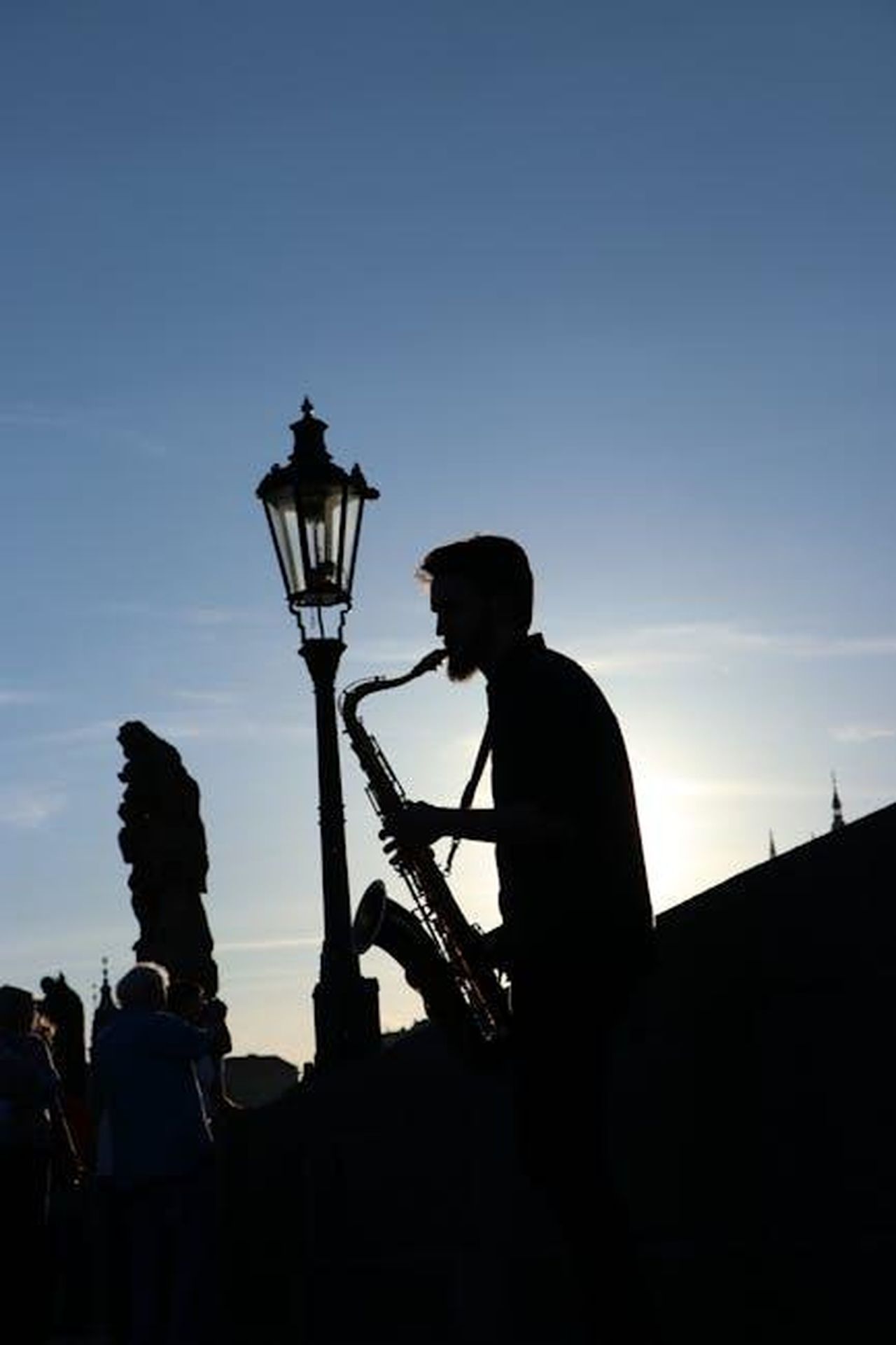 Chaos_The_Mansion_Murders_Analizza_la_Musica_di_Charles_Manson_cvFIaInFuR - Confidenze24 Source: Diana Room - pexels - A saxophonist performs as a silhouette against the setting sun on Prague's iconic Charles Bridge.