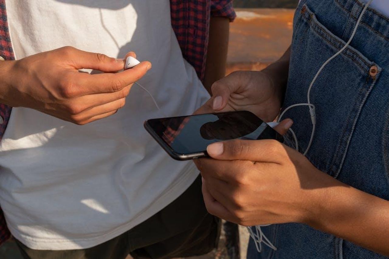 Chiusura_dellaccount_sui_social_media_8JWi2jU1UI - Confidenze24 Source: Ron Lach - pexels - Close-up of teenagers sharing music on a smartphone outdoors with earphones.