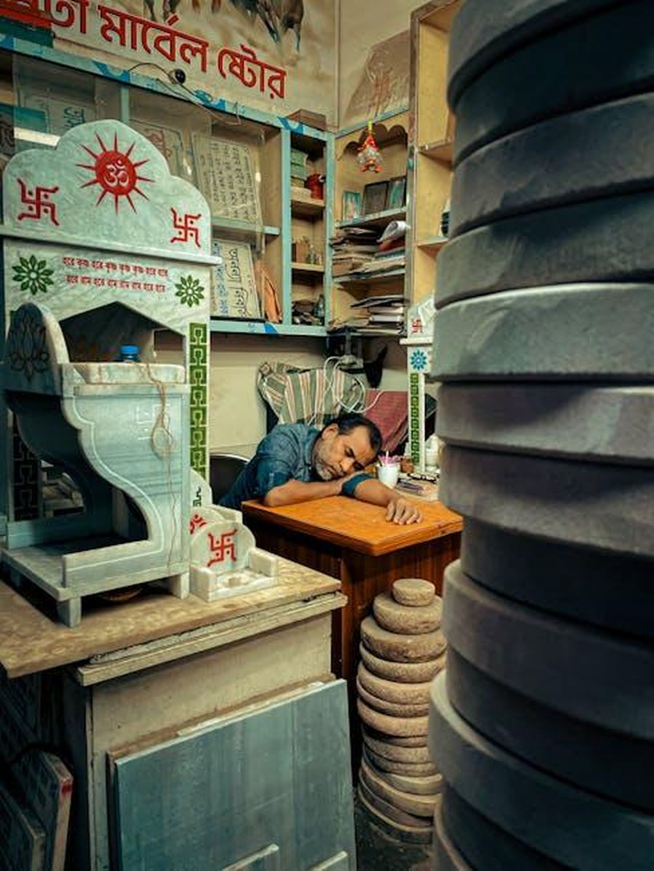 Chris_ha_avuto_difficolt_a_guardare_scene_intime_gLIfVzKiXw - Confidenze24 Source: Istiaque Ahmed - pexels - A man sleeps inside a Dhaka shop surrounded by religious artifacts and sculptures.