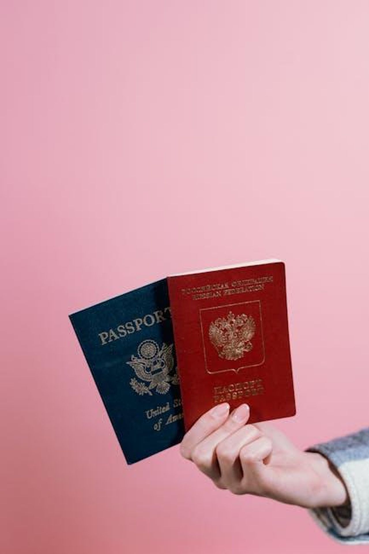 Cittadinanza_americana_nel_2012_Vaa7QLuhfH - Confidenze24 Source: Tima Miroshnichenko - pexels - Close-up of two passports held by a hand against a pink background.