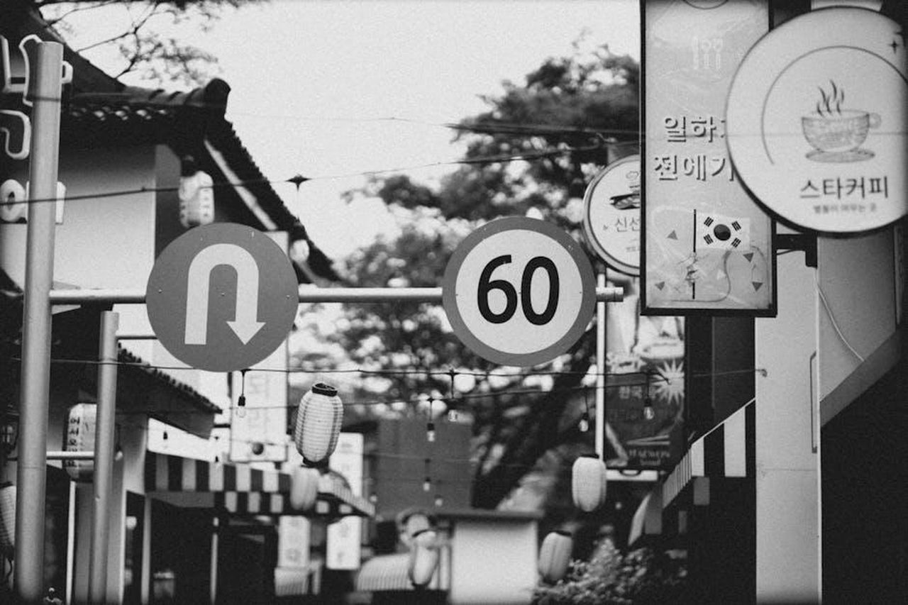 Coleen_sul_compiere_60_anni_RG2QaXDPoQ - Confidenze24 Source: Andhika Indra Pratama - pexels - Grayscale image of a Korean street with road signs and urban architecture.