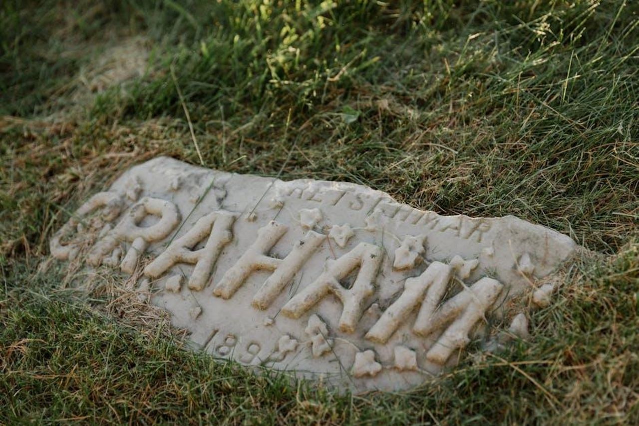 Collaborazione_con_Stephen_Graham_in_Adolescence_bvBrol6F35 - Confidenze24 Source: RDNE Stock project - pexels - Close-up of a worn gravestone partially covered by grass, displaying 'Graham.'