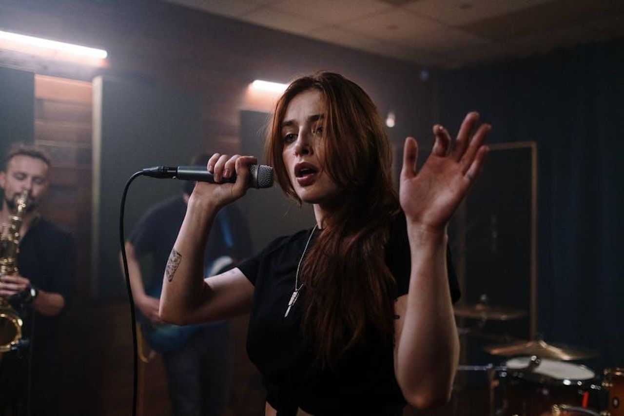 Collaborazioni_Future_SZA_e_Taylor_Swift_ZwnFYiJnRq - Confidenze24 Source: cottonbro studio - pexels - A passionate female vocalist performing live with a band in a studio setting, showcasing dynamic energy and musical talent.