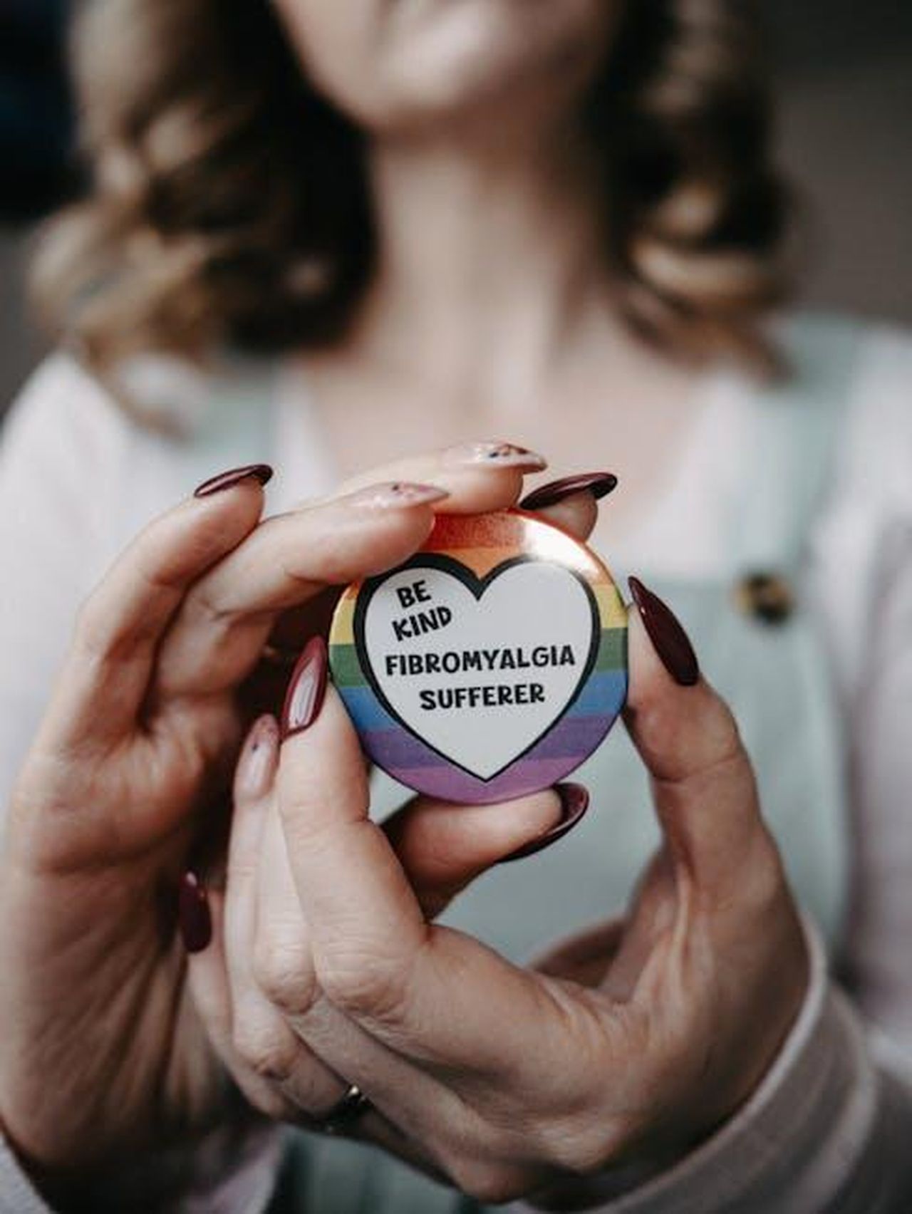 Collezione_Skechers_per_il_pickleball_stile_e_comfort_cI7adiuYuO - Confidenze24 Source: Lisa from Pexels - pexels - Hands holding a 'Be Kind - Fibromyalgia Sufferer' badge promoting awareness.