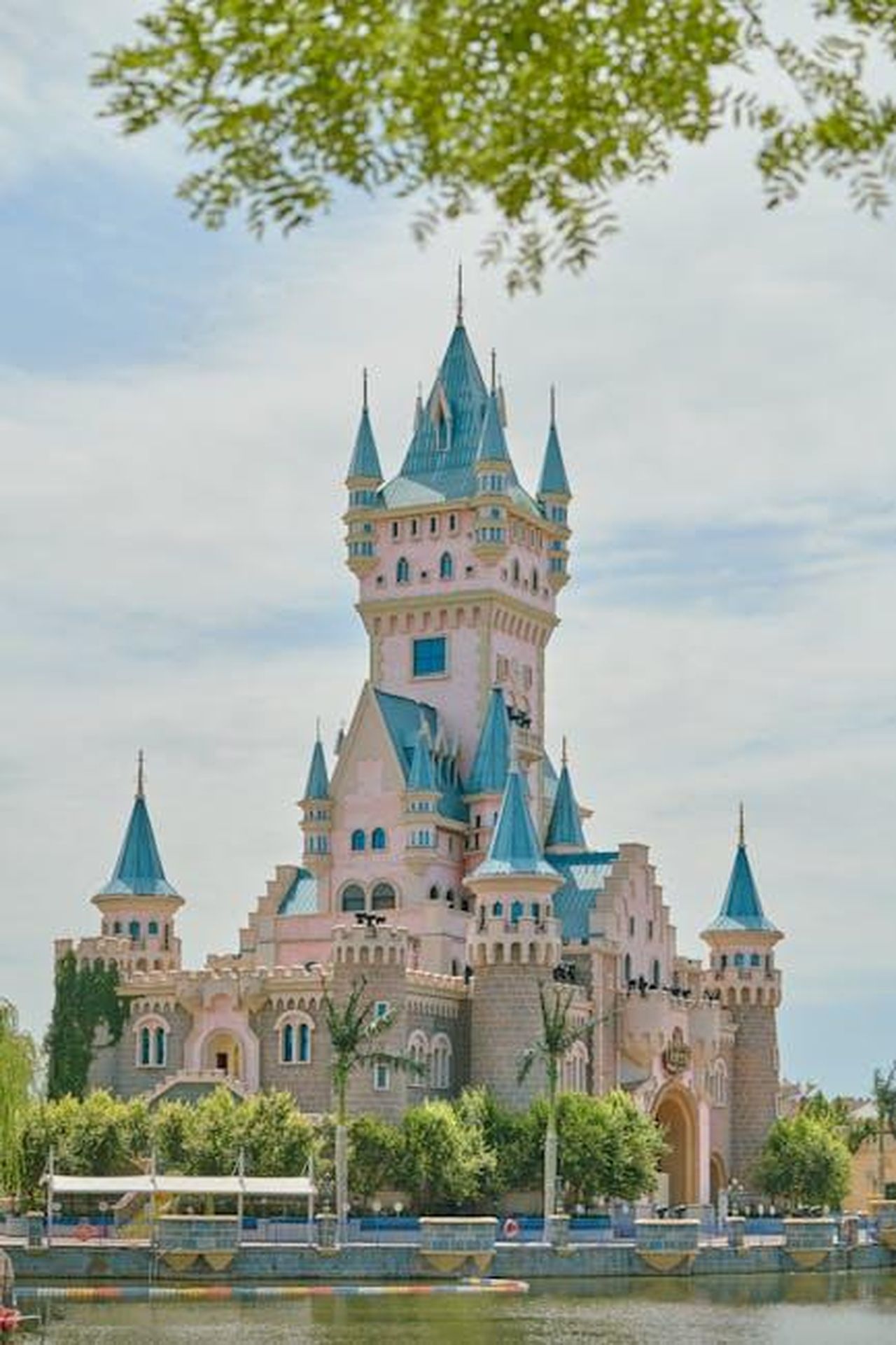 Collezione_di_lipgloss_Disney_le_principesse_protagoniste_qynbTcuyj5 - Confidenze24 Source: Suki Lee - pexels - Charming fairy tale castle with blue spires surrounded by lush greenery under a clear sky.