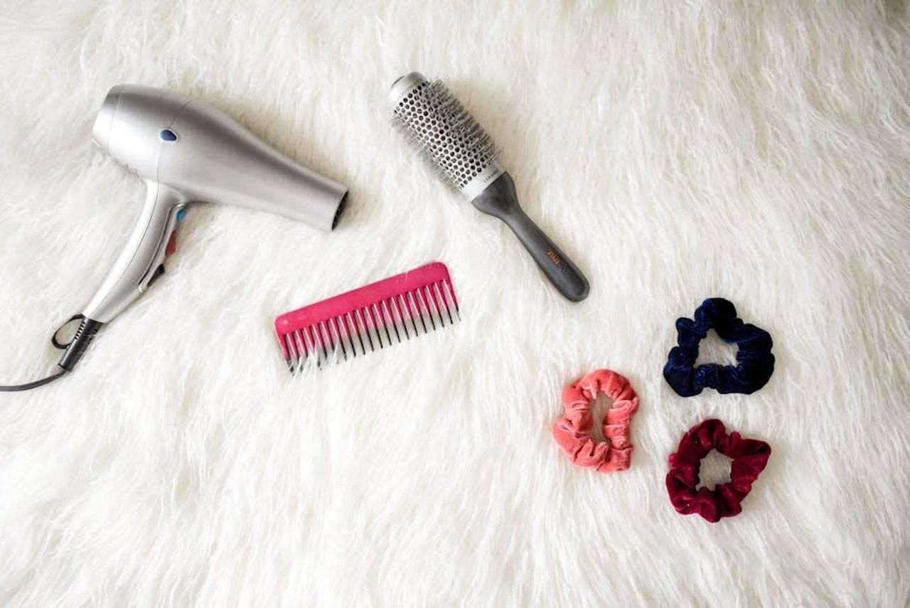 Come_applicare_il_trattamento_per_capelli_VrG0Gmr6dc - Confidenze24 Source: Element5 Digital - pexels - Flatlay of hairstyling tools including a hairdryer, brush, comb, and scrunchies on white fur.