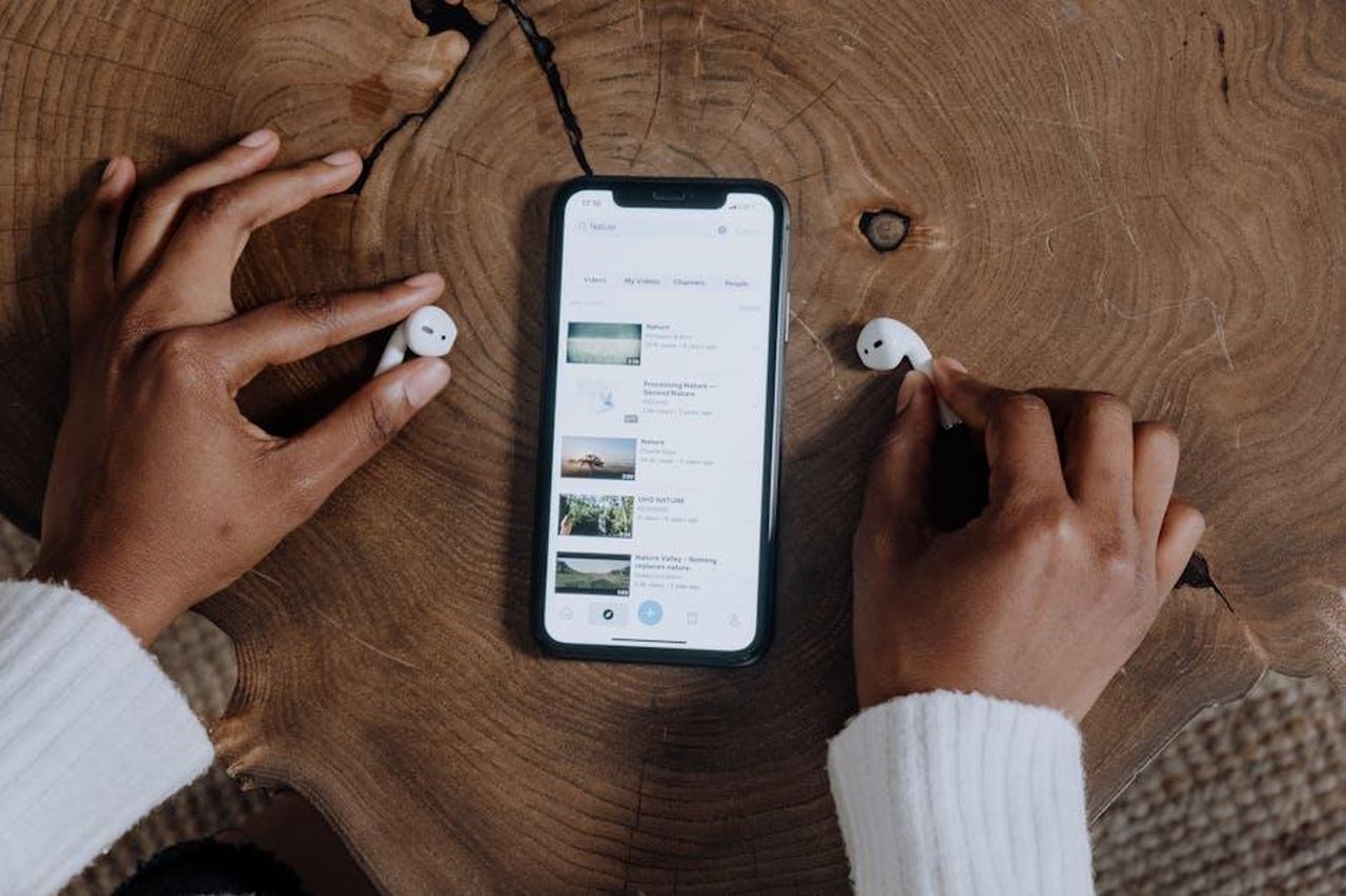 Come_hanno_reagito_i_fan_Oh8LndDVk2 - Confidenze24 Source: cottonbro studio - pexels - Hands interacting with smartphone and earbuds on a rustic wooden table, highlighting modern technology.