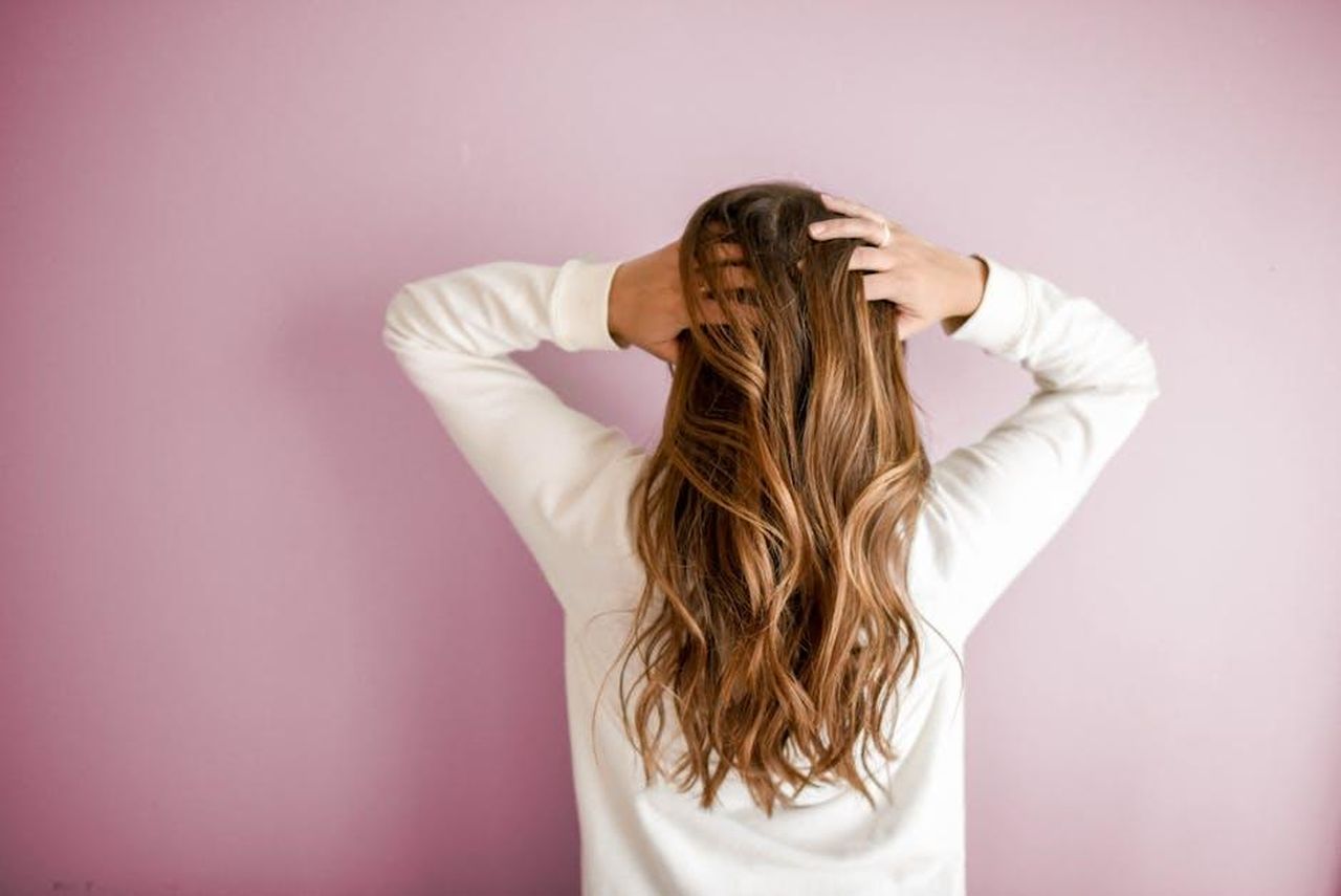 Come_utilizzare_il_SheaMoisture_Hydrate__Repair_Shampoo_SZV1moF620 - Confidenze24 Source: Element5 Digital - pexels - Back view of a woman with elegant long brown hair against a pink wall, showcasing stylish hair design.