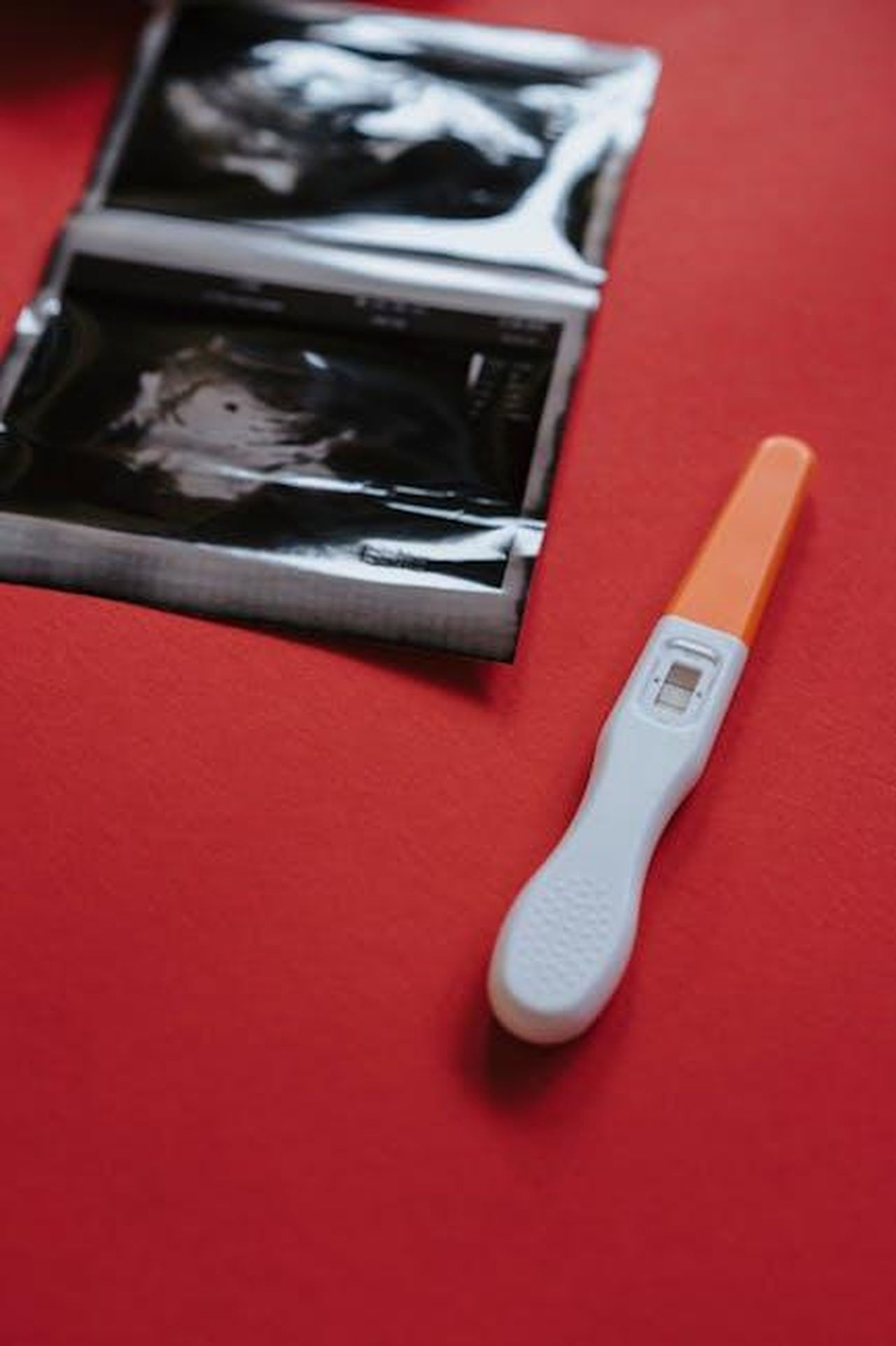Come_viene_trattata_la_sindrome_del_gemello_scomparso_dKsv8whSRW - Confidenze24 Source: olia danilevich - pexels - Close-up of a pregnancy test and ultrasound on a red surface, highlighting results.