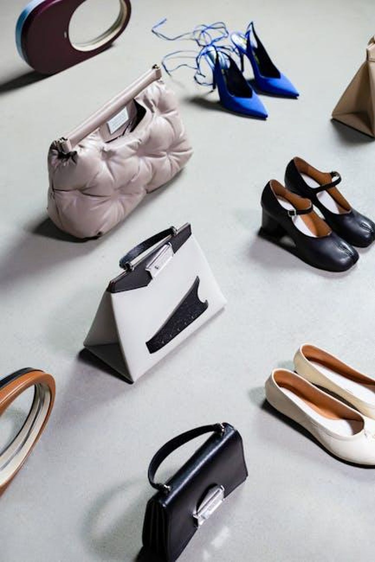 Commenti_affettuosi_e_avvertimenti_sui_designer_IPzggBiRh8 - Confidenze24 Source: Максим Баглаев - pexels - High-angled shot of stylish shoes and bags arranged on a white surface, exuding elegance and luxury.