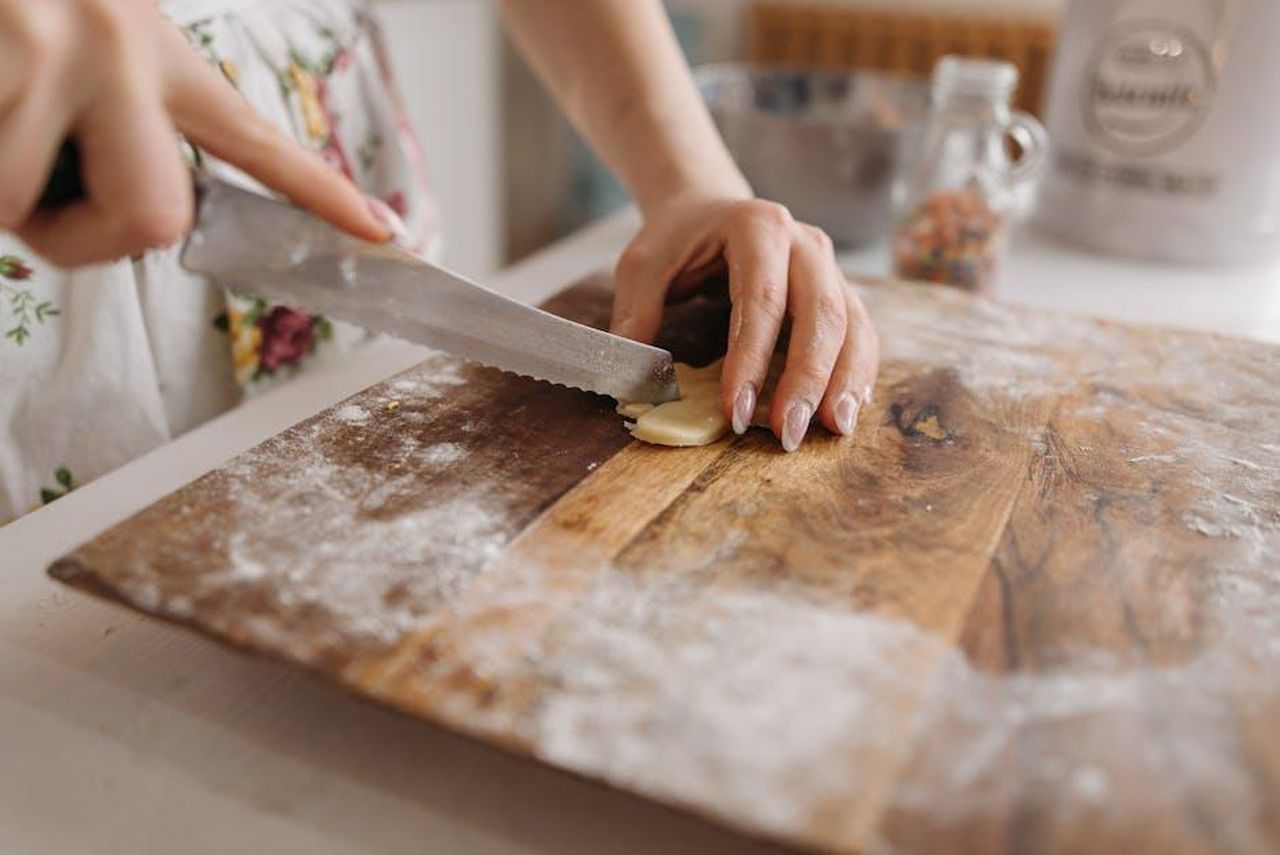 Consigli_per_la_preparazione_zY1EvIIKh1 - Confidenze24 Source: Pavel Danilyuk - pexels - Close-up of hands deftly slicing cookie dough on a floured wooden board in the kitchen.