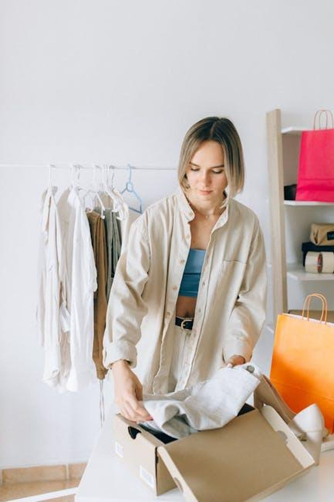 Consigli_per_lacquisto_rLeIEFgyPm - Confidenze24 Source: Nataliya Vaitkevich - pexels - A young woman organizing clothes in a stylish indoor setting, emphasizing modern fashion.