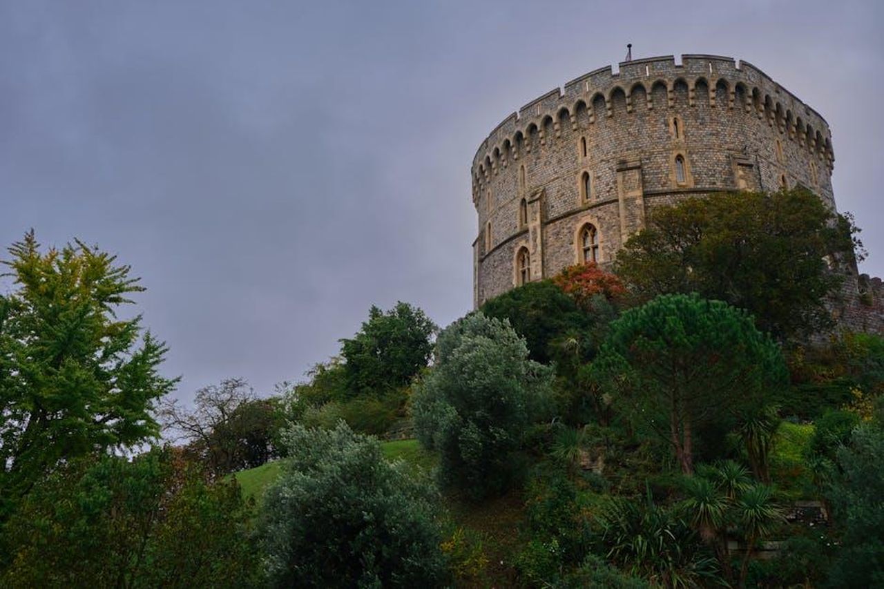 Contrasti_con_le_voci_del_passato_2KlkDOK1rY - Confidenze24 Source: Nick - pexels - View of Windsor Castle's stone structure amidst lush greenery under an overcast sky.