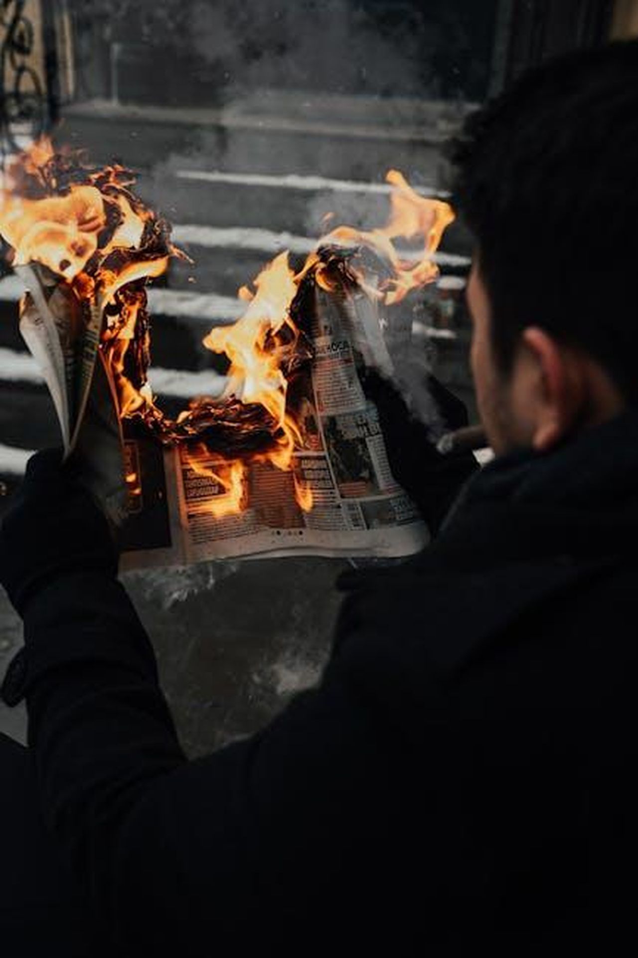 Controversie_passate_di_Jonathan_Majors_MdYAXQ6z9F - Confidenze24 Source: Nevzat Öztürk - pexels - A compelling shot of a man holding a burning newspaper, capturing a dramatic moment.