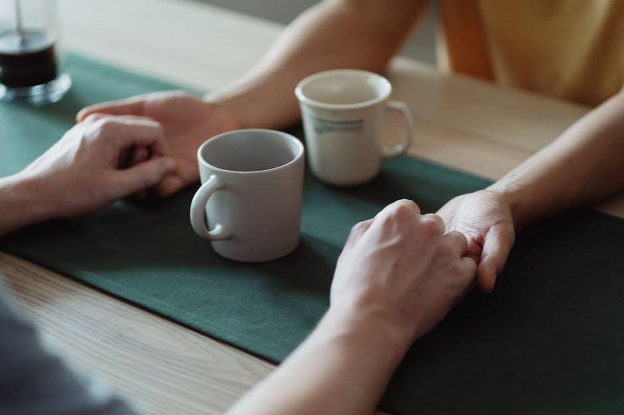 Conversazioni_significative_attraverso_i_libri_Drv5sulhk4 - Confidenze24 Source: Ketut Subiyanto - pexels - Close-up of hands holding across a table with coffee cups, conveying warmth and connection.