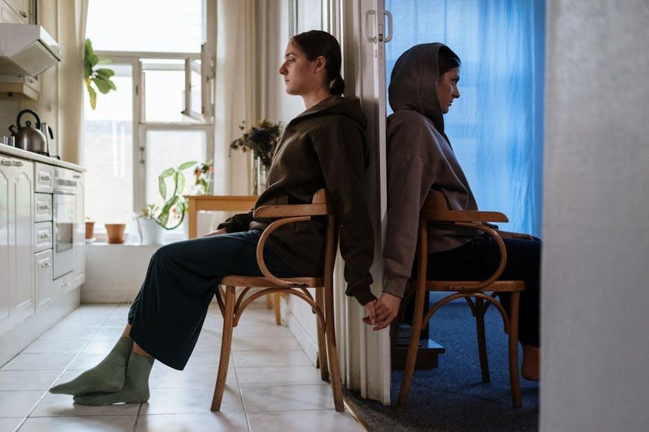 Cosa__la_psicosi_e_come_pu_essere_trattata_Nj1NcKucTZ - Confidenze24 Source: cottonbro studio - pexels - Two individuals seated back-to-back in chairs, highlighting emotion and mental health in an indoor setting.