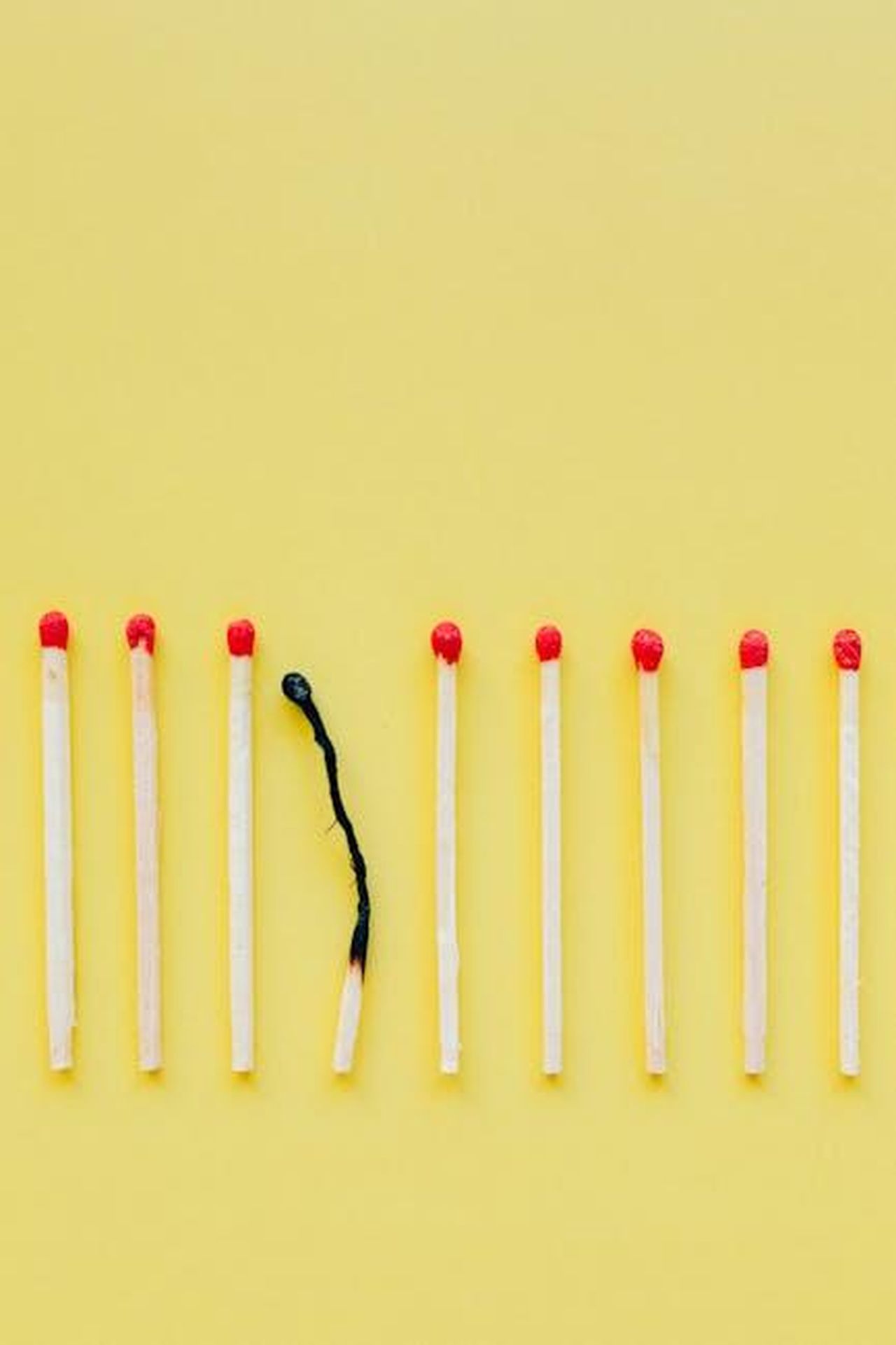 Cosa__la_sindrome_del_gemello_scomparso_fSTiMZqVY6 - Confidenze24 Source: Nataliya Vaitkevich - pexels - A line of matchsticks with one burned out symbolizes burnout and exhaustion against a yellow background.