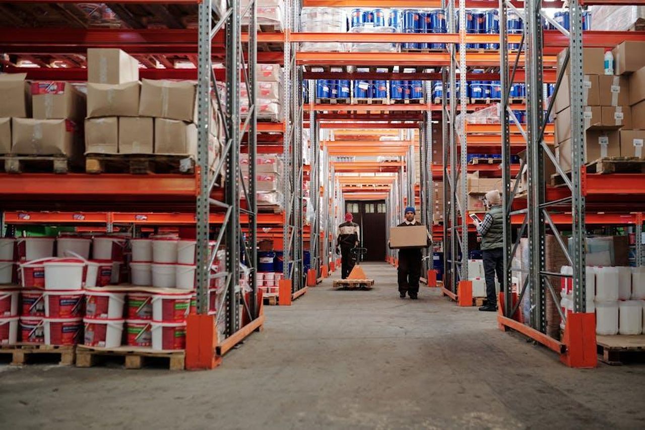 Cosa_aspettarsi_dai_Sussex_con_Maines_al_timone_oqLYWmRuTk - Confidenze24 Source: Tiger Lily - pexels - Warehouse interior showing workers handling boxes and organized shelves filled with products.