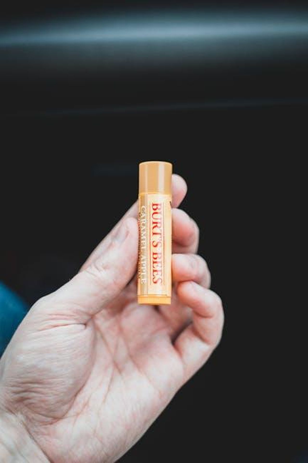 Cosa_dicono_gli_utenti_del_Julep_247_Lip_Treatment_0fu0b1zlTS - Confidenze24 Source: Erik Mclean - pexels - Close-up image of a hand holding Burt's Bees lip balm against a dark background.