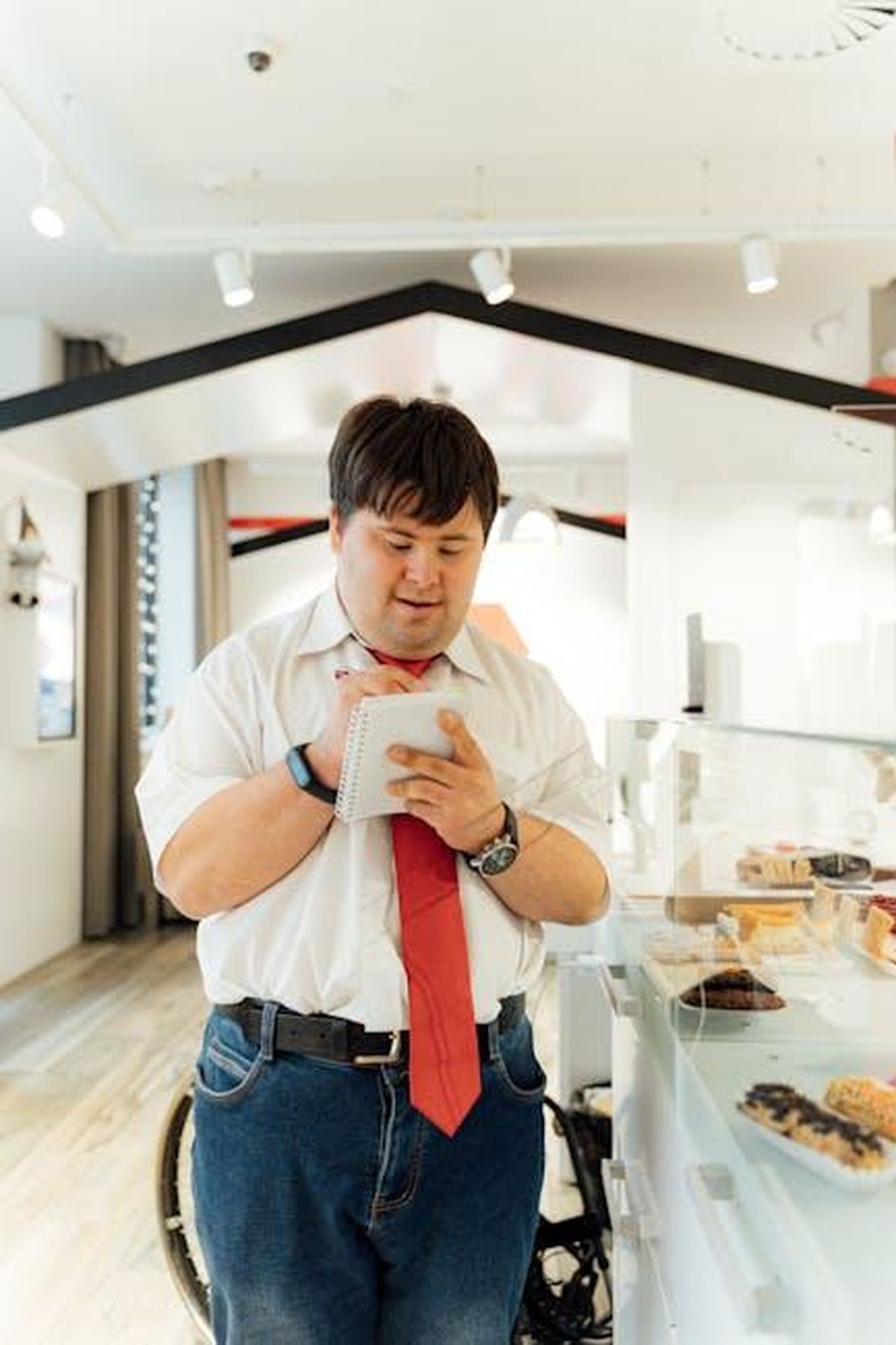 Cosa_dicono_gli_utenti_nl48lUjyc2 - Confidenze24 Source: Antoni Shkraba - pexels - Adult man in red tie writing in a notepad next to a pastry display in a modern indoor setting.