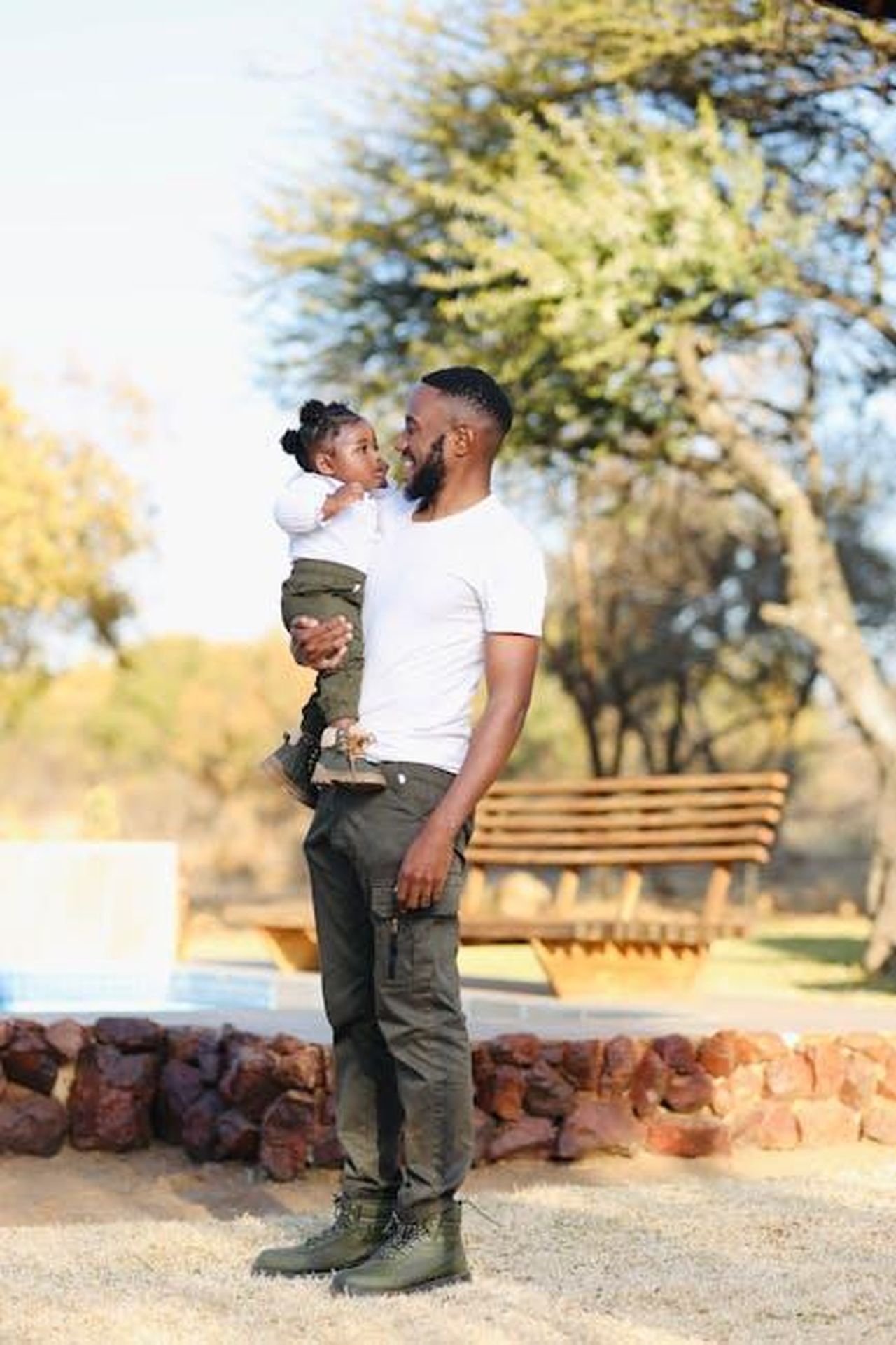 DDG_e_le_Difficolt_di_Vedere_il_Figlio_89OAJSB4hM - Confidenze24 Source: Michael Zolowere Phiri - pexels - A father holding his young child in an outdoor setting, showcasing a serene family moment.