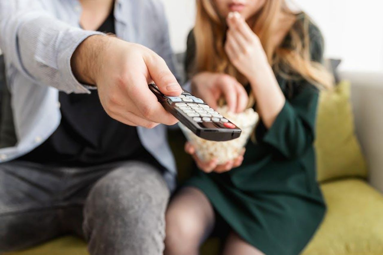 Data_di_Uscita_del_Finale_37HJOKz8CD - Confidenze24 Source: JESHOOTS.com - pexels - A couple enjoying a relaxing movie night, sitting on a sofa with popcorn and a TV remote.