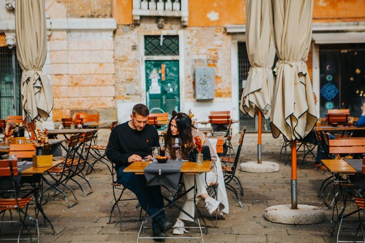 Dentro_la_relazione_di_Jesy_Nelson_con_Zion_Foster_EQVgIYeFCs - Confidenze24 Source: Helena Jankovičová Kováčová - pexels - A couple enjoys a meal at an outdoor cafe in a charming European setting.