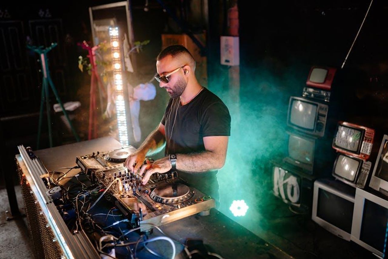 Dettagli_sul_successo_di_Watson_dsTeICtg5w - Confidenze24 Source: Yan Krukau - pexels - DJ performing on turntables amidst vibrant lights and retro TVs at a lively nightclub event.