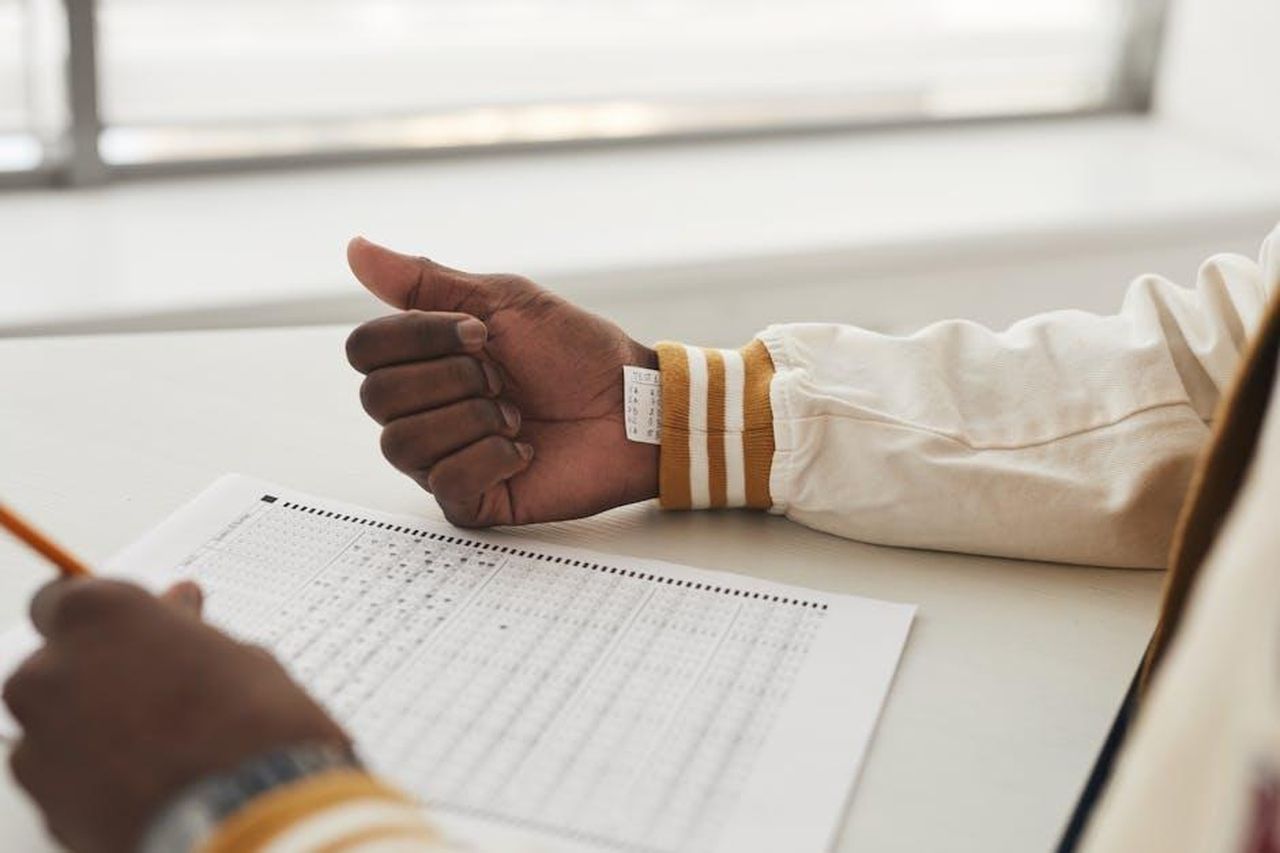 Dettagli_sulla_Causa_e_le_Accuse_nUKoWmAwO4 - Confidenze24 Source: Andy Barbour - pexels - Close-up of a student cheating in an exam by hiding notes under a sleeve during a test.
