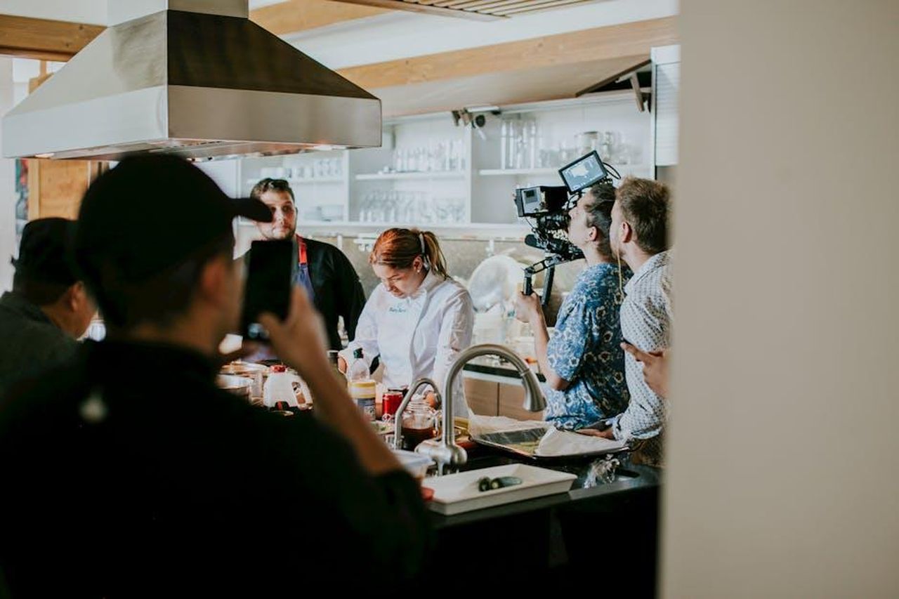 Dettagli_sullepisodio_di_domani_jEvbkXjFnf - Confidenze24 Source: Amar Preciado - pexels - Behind the scenes view of film crew capturing a cooking show in a professional kitchen setting.