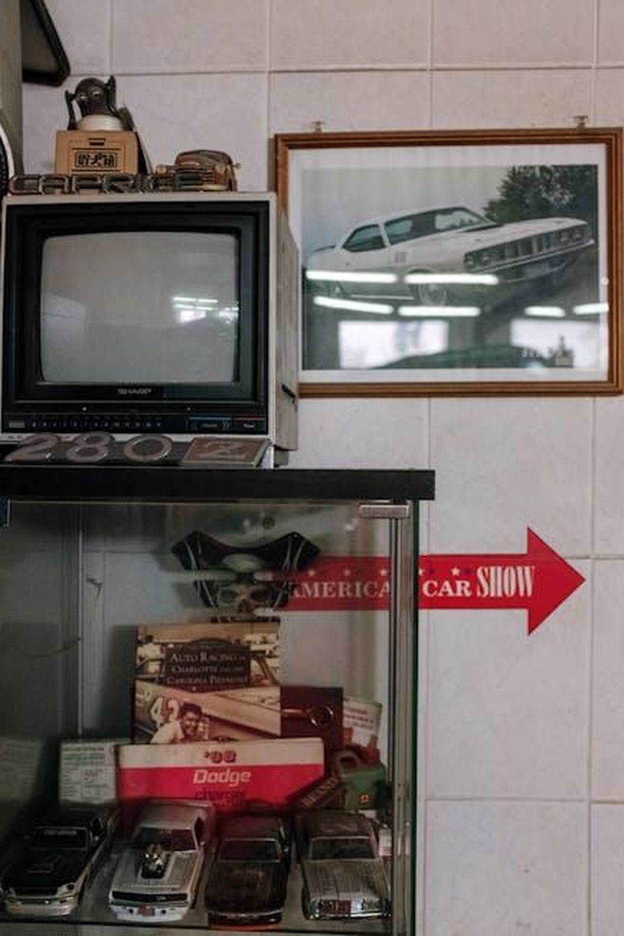 Dettagli_sullepisodio_finale_pBoXKXqBhW - Confidenze24 Source: cottonbro studio - pexels - A vintage car collection in a garage with a classic TV and framed photograph decor.