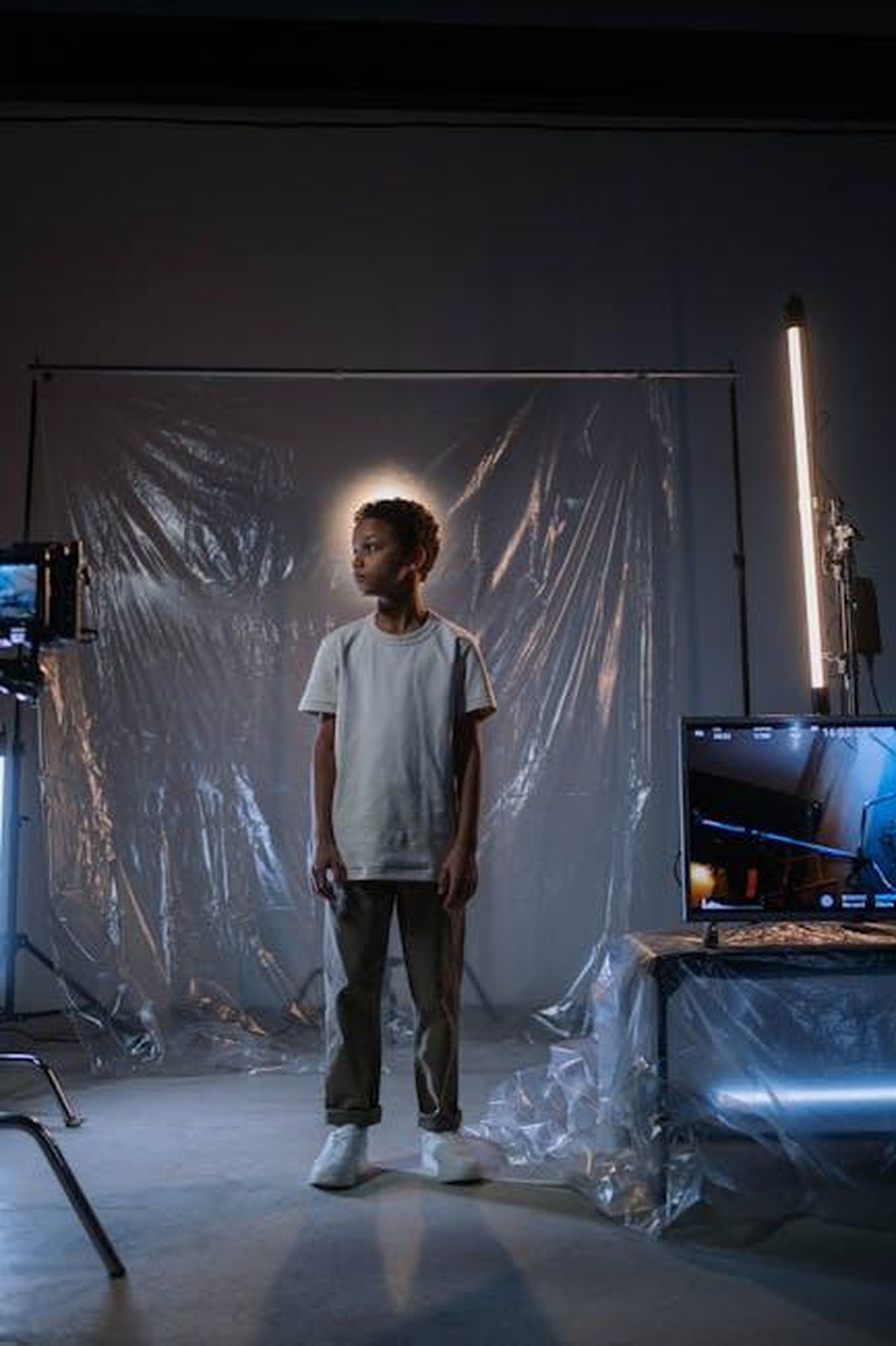 Dinamiche_tra_i_personaggi_nella_terza_stagione_Hd6ocQmd2f - Confidenze24 Source: cottonbro studio - pexels - A young boy stands in a contemporary studio setting with reflective surfaces and lighting.