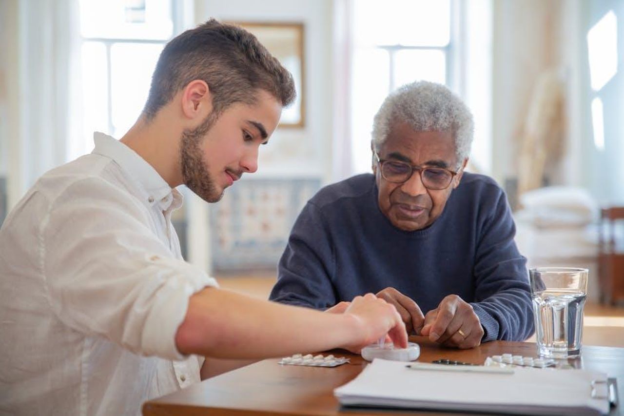 Discussione_sullinvecchiamento_e_la_bellezza_tra_Ike_Barinholtz_e_Dax_Shepard_caJgUgiF3H - Confidenze24 Source: Kampus Production - pexels - A young volunteer helps an elderly man manage his medication at a nursing home.
