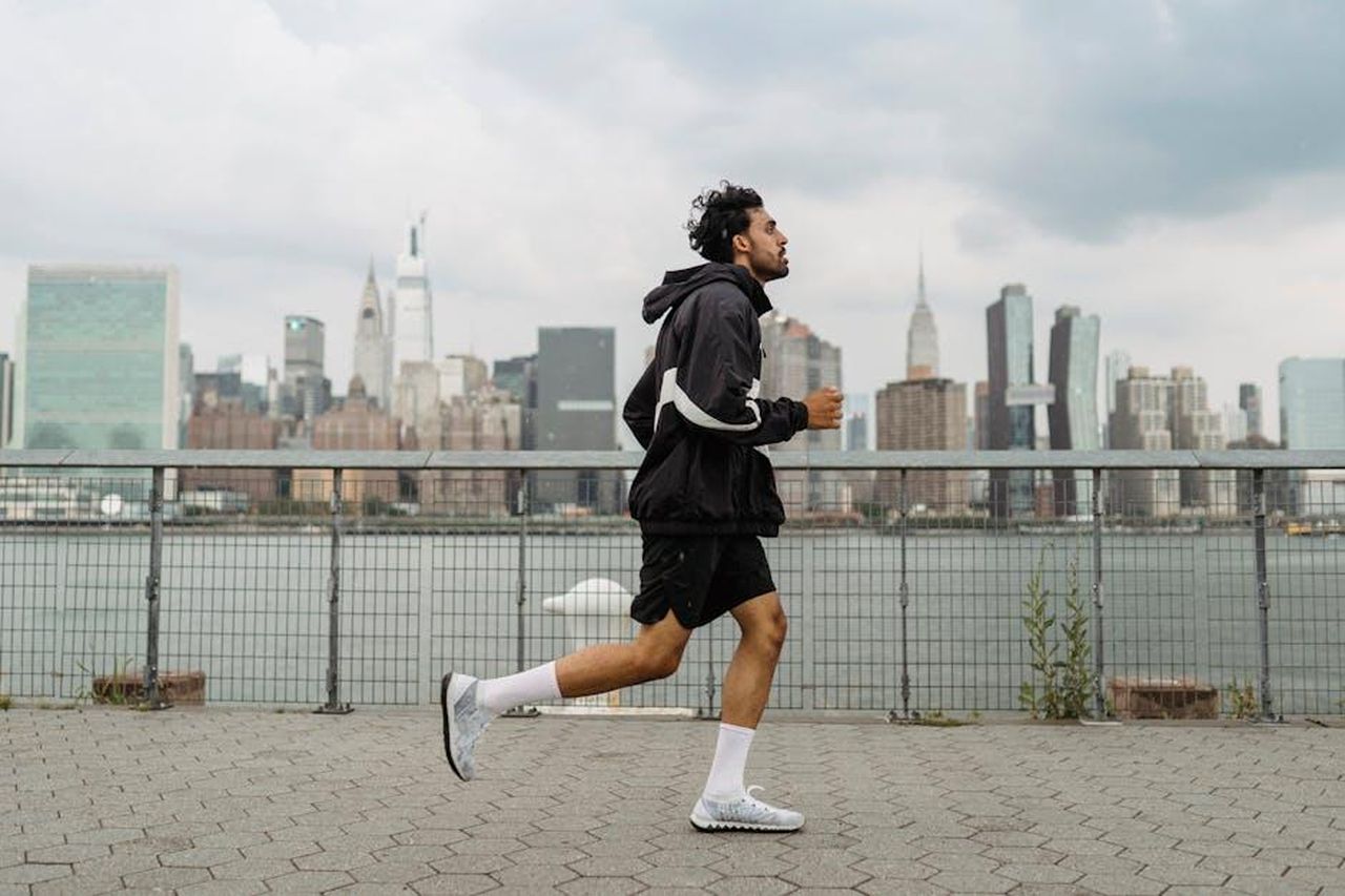 Disponibilit_e_acquisto_delle_On_Cloudnova_2_c8fFL5vX2w - Confidenze24 Source: Ketut Subiyanto - pexels - Adult man jogging along a waterfront with the New York City skyline in the background, exuding a vibrant urban lifestyle.