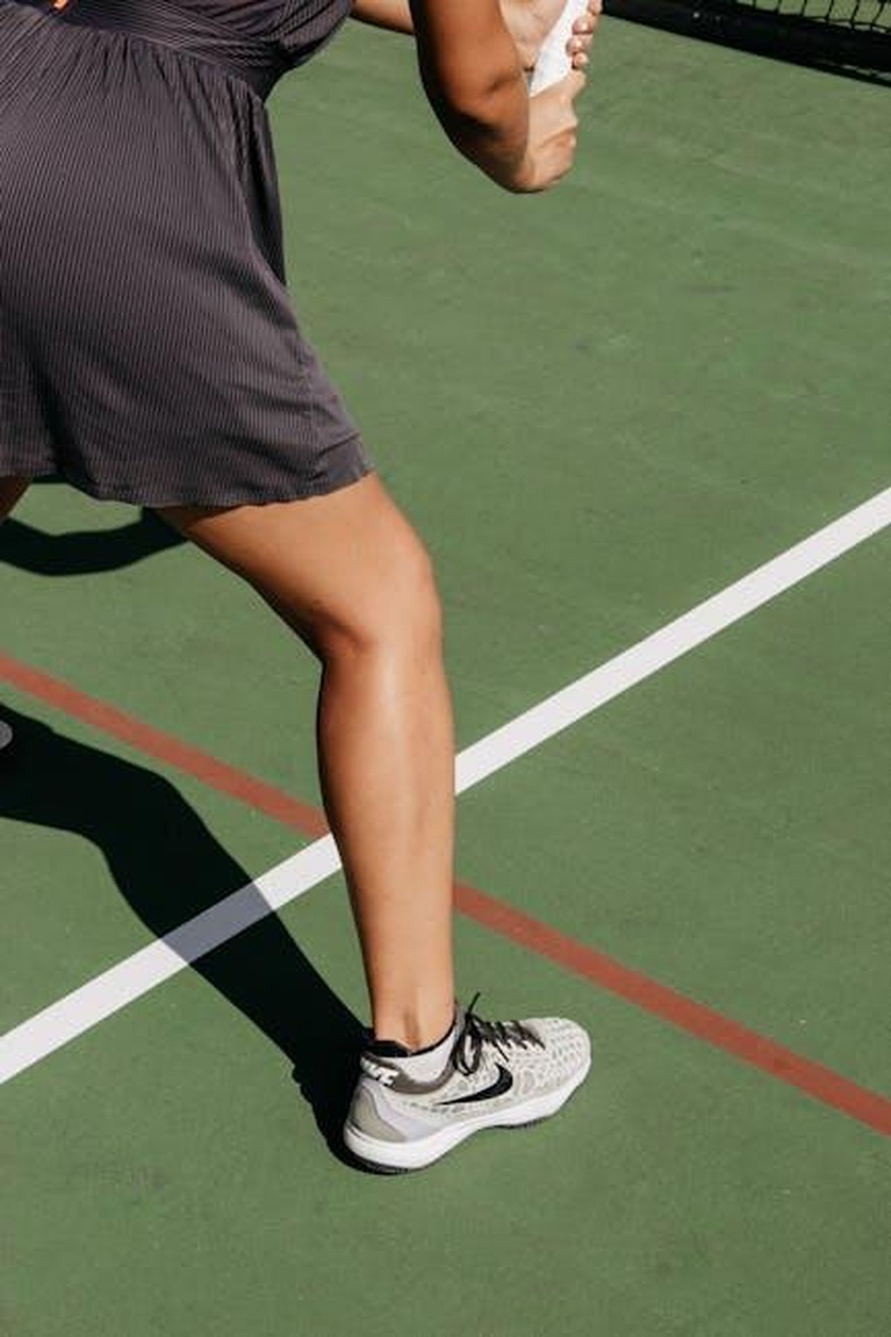 Disponibilit_e_prezzi_delle_On_Cloudsurfer_2_crH4IzMQxD - Confidenze24 Source: Julia Kuzenkov - pexels - Close-up of a woman on an outdoor tennis court preparing to serve.
