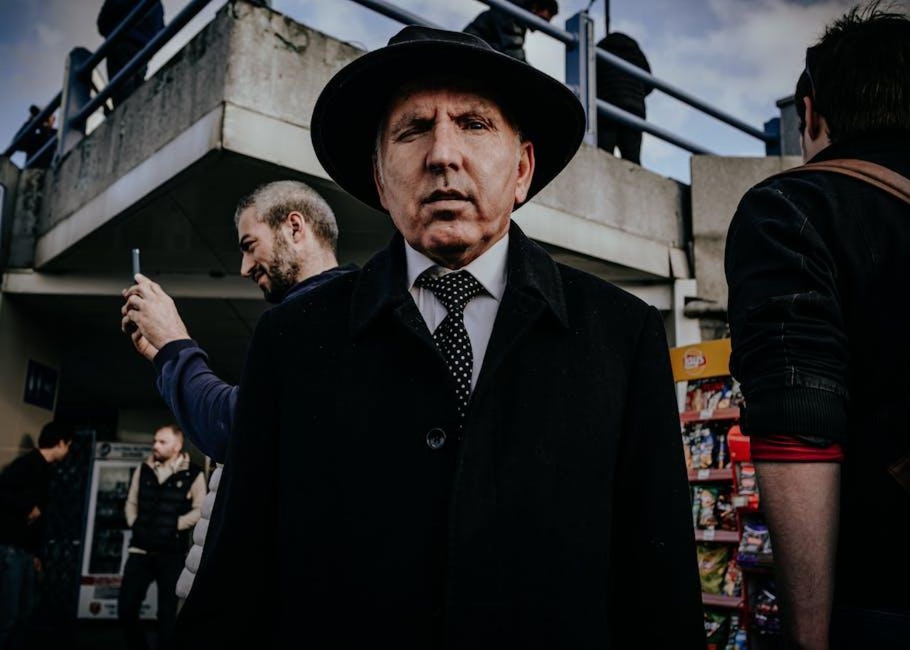 Documentario_su_Halyna_Hutchins_in_arrivo_p1zqGwUv2d - Confidenze24 Source: İsacan Çiçek - pexels - A man in a suit and hat stands prominently in a bustling urban street setting.