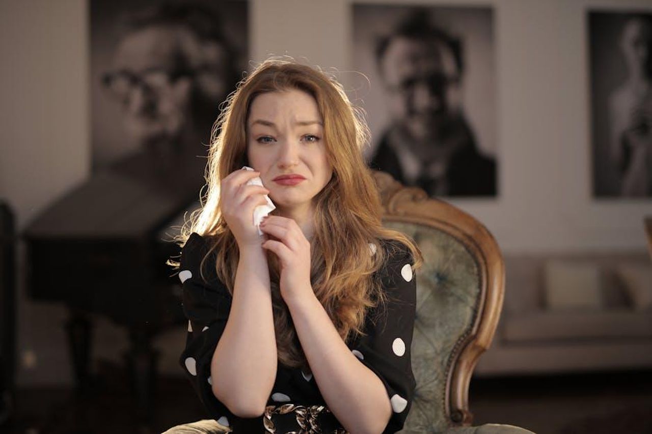 Dolly_Parton_e_la_perdita_di_Carl_Dean_oWLGkGkMDf - Confidenze24 Source: Andrea Piacquadio - pexels - A woman sitting in a vintage chair indoors, showing emotions and holding tissues.