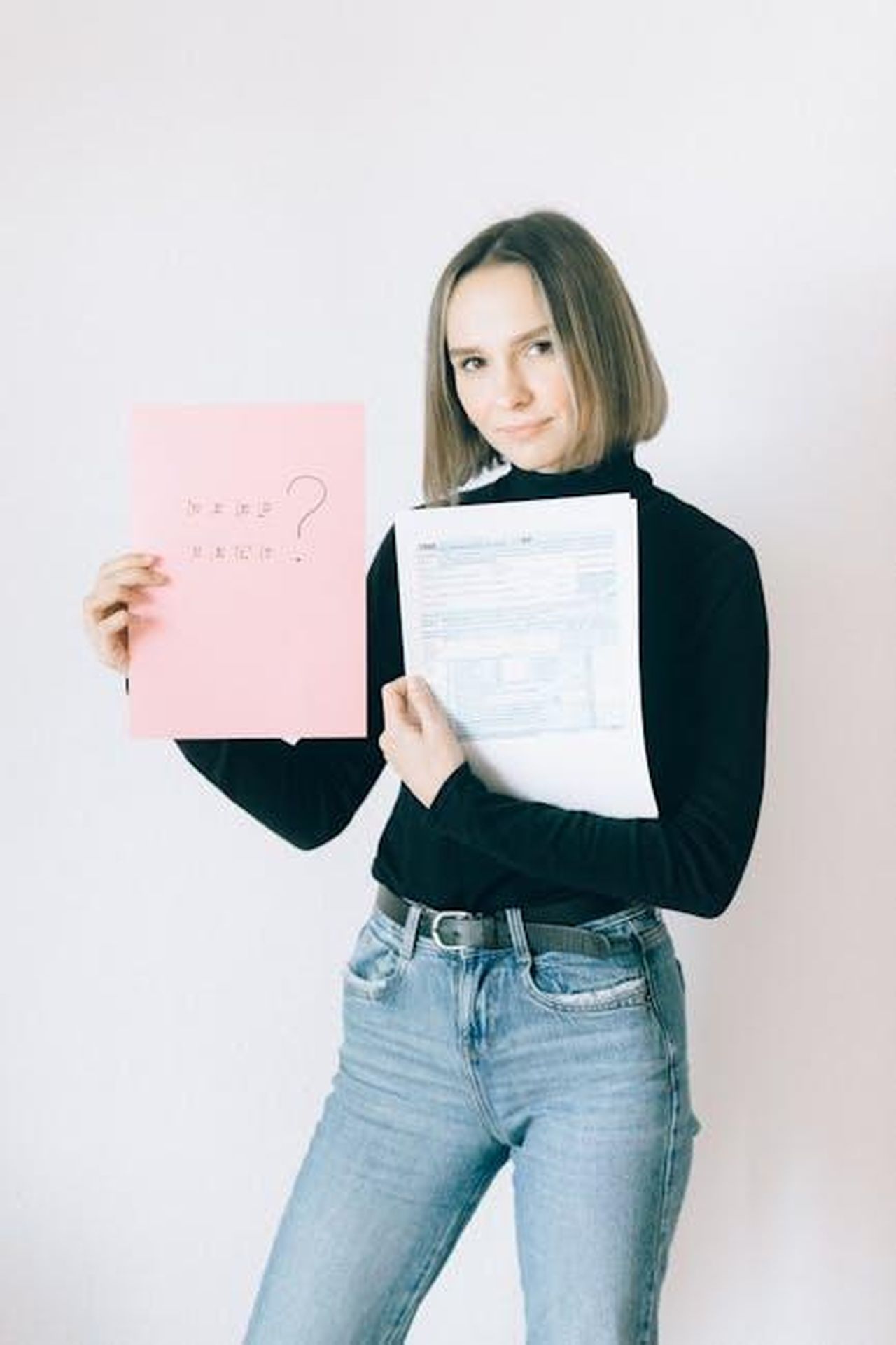Domande_sulla_necessit_di_Meghan_e_Harry_qwNUuZoAUy - Confidenze24 Source: Nataliya Vaitkevich - pexels - Woman in turtleneck holding tax forms and a pink question sheet indoors.